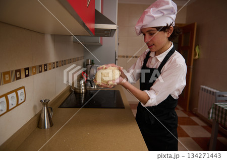 Young Chef Preparing Dough In A Kitchen With Apron And White Chef Hat 134271443