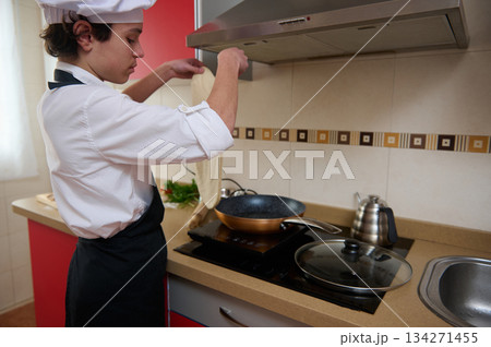 Young Chef Tossing Pizza Dough in Modern Kitchen While Cooking on Stovetop 134271455
