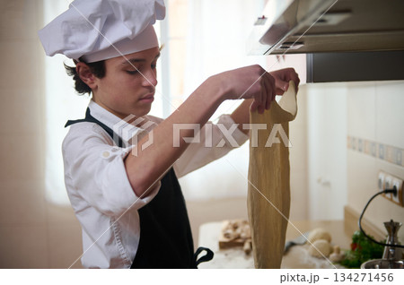 Young Chef Makes Flat Dough Sheet In Bright Kitchen, Focusing On Culinary Craft 134271456