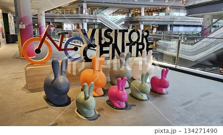 A vibrant visitor centre display with colorful rabbits, a stylized bicycle, and gradient pillars creates a playful, 134271490