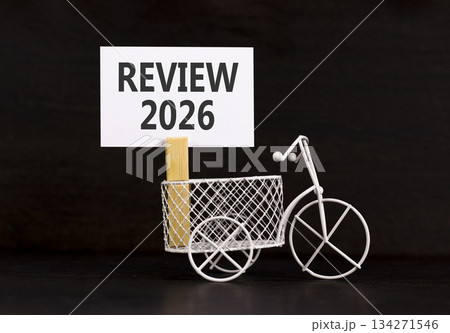 Review 2026 symbol. Concept words Review 2026 on beautiful white paper on wooden clothespin. Beautiful black background. Beautiful miniature bicycle. Business and review 2026 concept. Copy space. 134271546