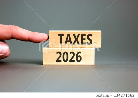 Taxes 2026 new year symbol. Concept words Taxes 2026 on beautiful wooden blocks. Beautiful grey paper background. Businessman's hand. Business and taxes 2026 new year concept. Copy space. Taxes 2026 new year symbol. Concept words Taxes 2026 on beautiful wooden blocks. Beautiful grey paper background. Businessman's hand. Business and taxes 2026 new year concept. Copy space. 134271562