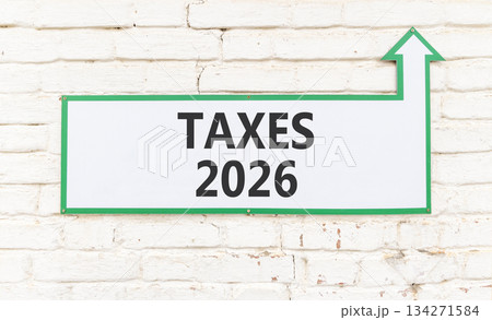 Taxes 2026 new year symbol. Concept words Taxes 2026 on beautiful white sign with arrow. Beautiful old white brick wall background. Business and taxes 2026 new year concept. Copy space. Taxes 2026 new year symbol. Concept words Taxes 2026 on beautiful white sign with arrow. Beautiful old white brick wall background. Business and taxes 2026 new year concept. Copy space. 134271584