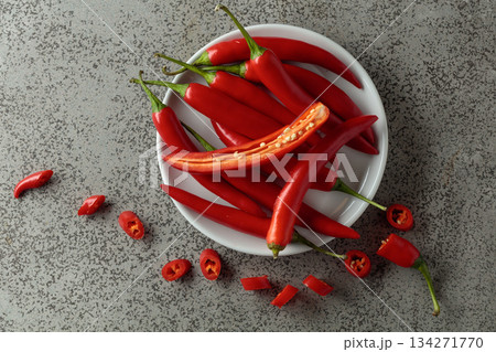 Fresh red chili peppers with green stems on a gray stone table. Fresh red chili peppers with green stems on a gray stone table. 134271770