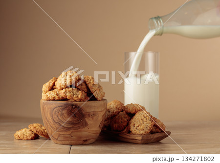 Oatmeal cookies and milk sit on a kitchen table. Oatmeal cookies and milk sit on a kitchen table. 134271802