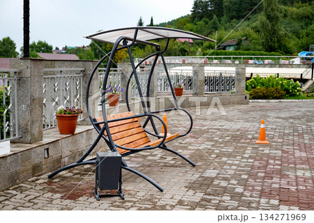 Outdoor swing bench with canopy on a tiled patio. 134271969