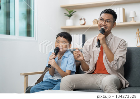 Father and son singing together with microphones at home 134272329