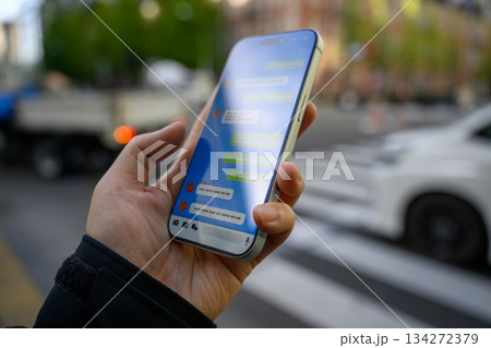 路上でスマホでチャットをする手元 134272379