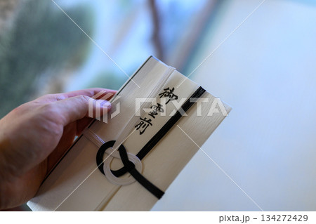 御霊前と書かれた不祝儀袋を差し出す日本人男性の手元（上半身・顔なし） 134272429