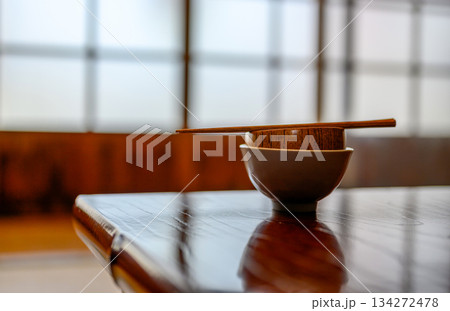 艶やかな木製テーブルに置かれた和風の茶碗と箸 艶やかな木製テーブルに置かれた和風の茶碗と箸 134272478