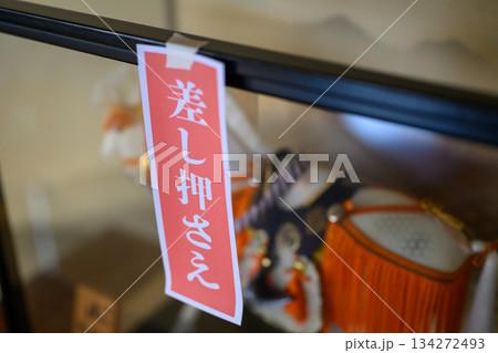 ケースに飾られた武者人形に貼られた「差し押さえ」の赤札 134272493