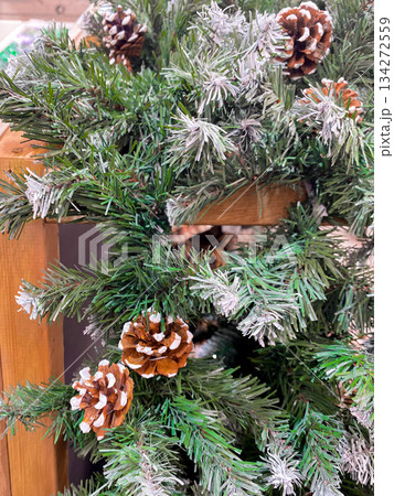 Beautifully crafted winter decor with realistic pinecones and frosted greenery. Wooden backdrop, natural elements. Warm, inviting atmosphere, perfect for celebrating Christmas or New Year 134272559