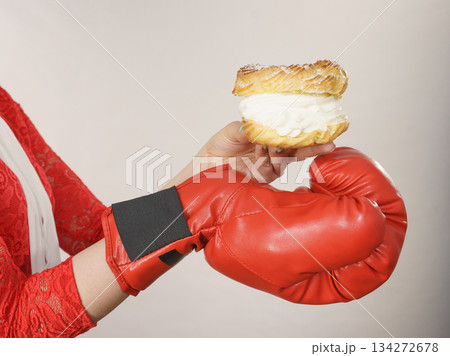 Woman fighting off bad food, boxing cream puff cake Woman fighting off bad food, boxing cream puff cake 134272678