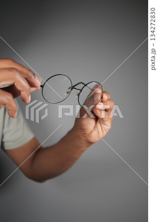 Hands hold round glasses against plain background 134272830