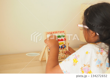 Child plays with counting beads at a table in the room 134272832