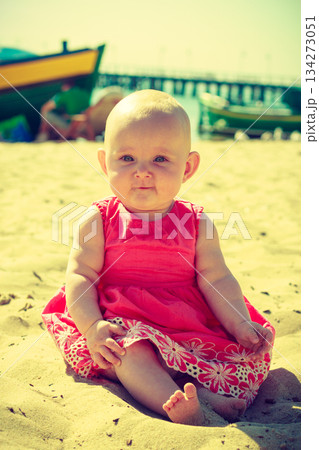 Little baby sitting and playing on beach 134273051