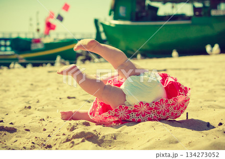 Small child fell over on the sand. Small child fell over on the sand. 134273052