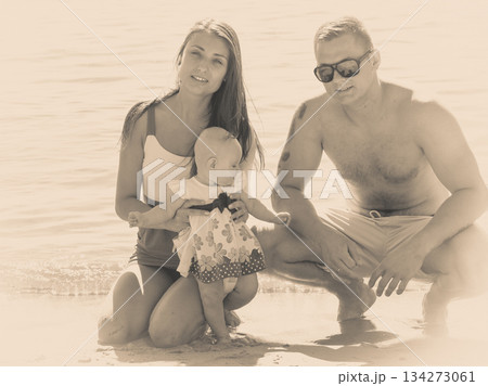 Two adult and baby posing near water 134273061