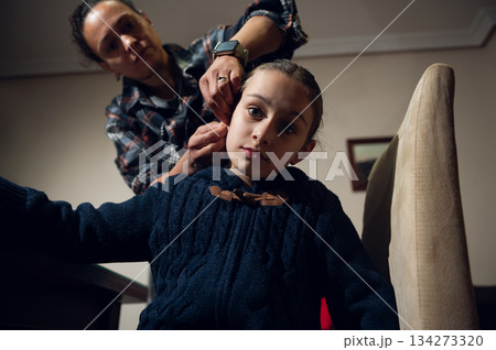 Caring Moment As An Adult Fixes A Little Girl's Hair In A Cozy Home Setting Caring Moment As An Adult Fixes A Little Girl's Hair In A Cozy Home Setting 134273320