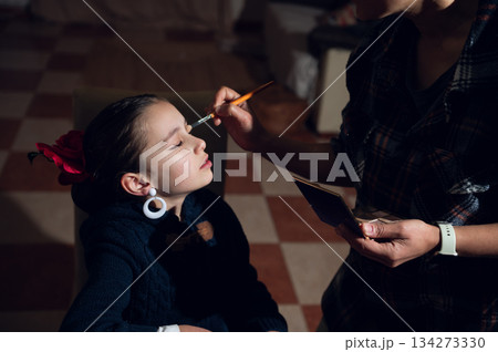 Young Girl Receives Makeup Application From Caring Adult In Soft Indoor Lighting 134273330