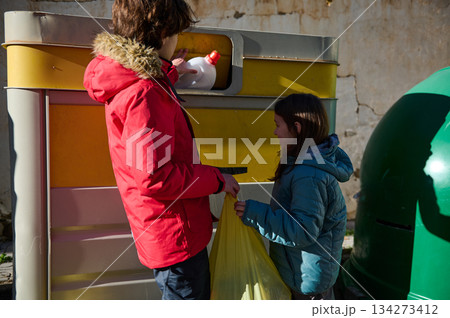 Parent And Child Recycling Together At Outdoor Street Bin With A Green Globe In Background 134273412