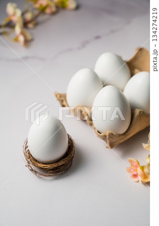 Easter spring background. Egg in a nest. Eggs box with flowers. Minimalistic 134274219