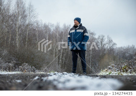 Adult happy man walks in winter park wearing blue sports jacket. Winter walk in frosty forest. Healthy season lifestyle. Outdoors. 134274435