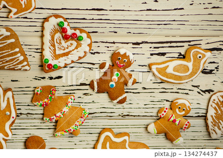 Gingerbread cookies with white and colorful icing are placed around rustic planks. Gingerbread cookies with white and colorful icing are placed around rustic planks. 134274437