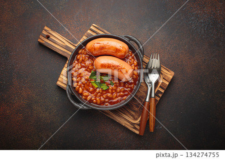 Baked beans tomato sauce grilled sausages cast iron pan English breakfast 134274755
