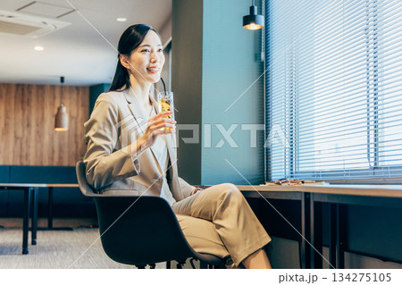 オフィスでドリンクを飲むビジネスウーマン 134275105