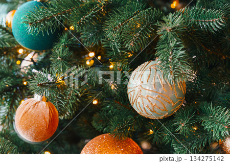 Sparkling christmas tree ornaments in gold and teal on warm holiday lights background 134275142