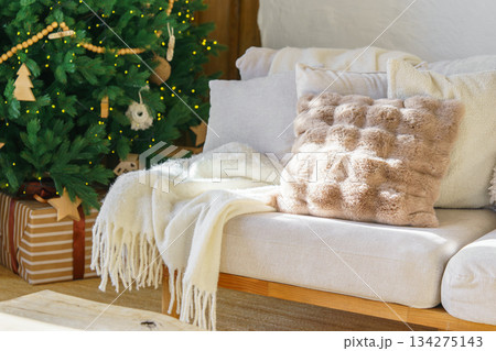 Cozy living room with decorated Christmas tree, warm sofa textiles and wrapped gifts for holidays Cozy living room with decorated Christmas tree, warm sofa textiles and wrapped gifts for holidays 134275143