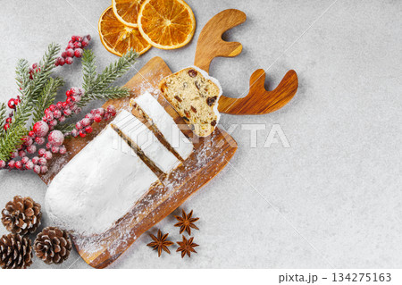 Traditional sliced Christmas stollen loaf with raisins and powdered sugar on wooden cutting board 134275163
