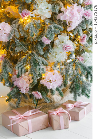 Wrapped presents, gift boxes with pink ribbons on white floor under festive holiday Christmas tree 134275176