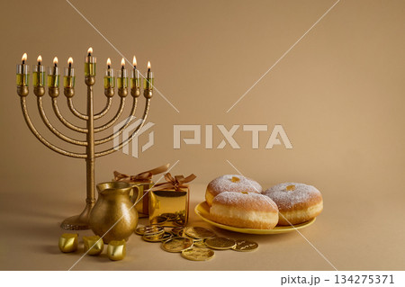 Hanukkah Celebration Setup. A menorah with lit candles, donuts, gelt, and gifts 134275371