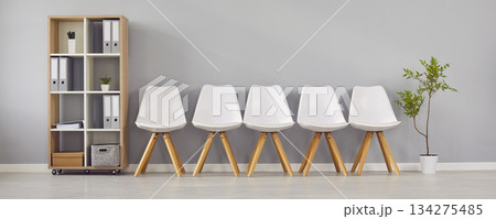 Waiting room with a row of chairs, a shelf and a green plant in a modern business office 134275485