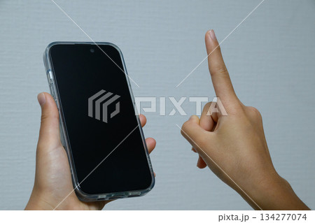 スマートフォンを指差して操作する手元 134277074