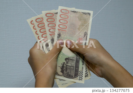 1万円札の束を数える手 134277075