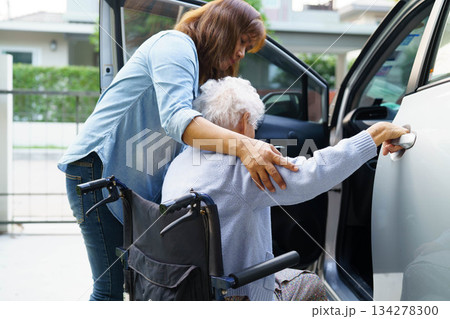 Caregiver help Asian elderly woman disability patient use wheelchair to get in car. 134278300