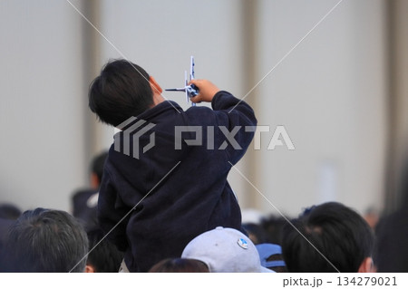 肩車の上でブルーインパルスの模型で遊ぶ少年 134279021