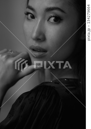 A beautiful Asian girl with black hair in a white dress against a yellow wall. Feminine attractiveness. A person with an aesthetically pleasing facial structure. A model for makeup and hairstyle 134279664