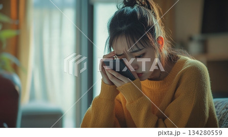 スマホを見つめ悲しそうな表情を浮かべる女性8 134280559