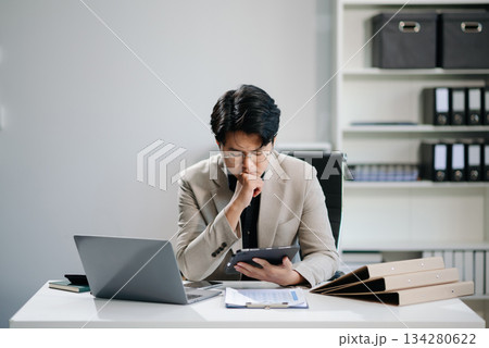Young businessman working with working notepad, tablet and laptop documents talking on the smartphone, tablet and laptop 134280622