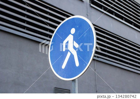 Minimalist urban scenery with prominent blue pedestrian sign emphasizing safety passage Minimalist urban scenery with prominent blue pedestrian sign emphasizing safety passage 134280742