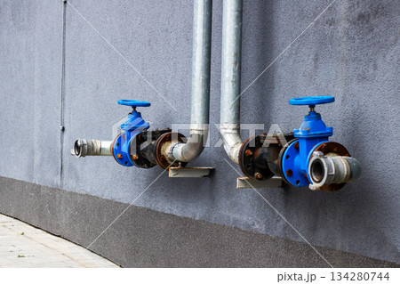 Industrial exterior scene featuring aged water valves and weathered infrastructure components 134280744