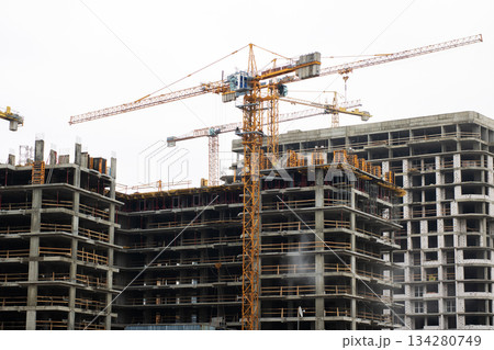 Construction rising under cloudy skies, Building site bustling with cranes and workers 134280749