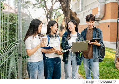 Young Asian People college students and a female student group work at the campus park in morning with her friend Young Asian People college students and a female student group work at the campus park in morning with her friend 134280817