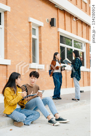 Young Asian People college students and a female student group work at the campus park in morning with her friend Young Asian People college students and a female student group work at the campus park in morning with her friend 134280914