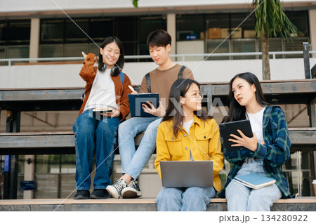 Young Asian People college students and a female student group work at the campus park in morning with her friend Young Asian People college students and a female student group work at the campus park in morning with her friend 134280922