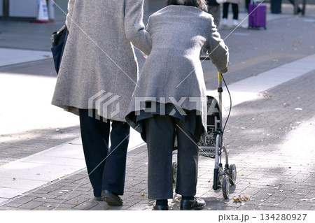 日本の横浜都市景観 師走…高齢化社会　四輪歩行器（四輪歩行車）の高齢女性。介助の女性が支えるが… 134280927